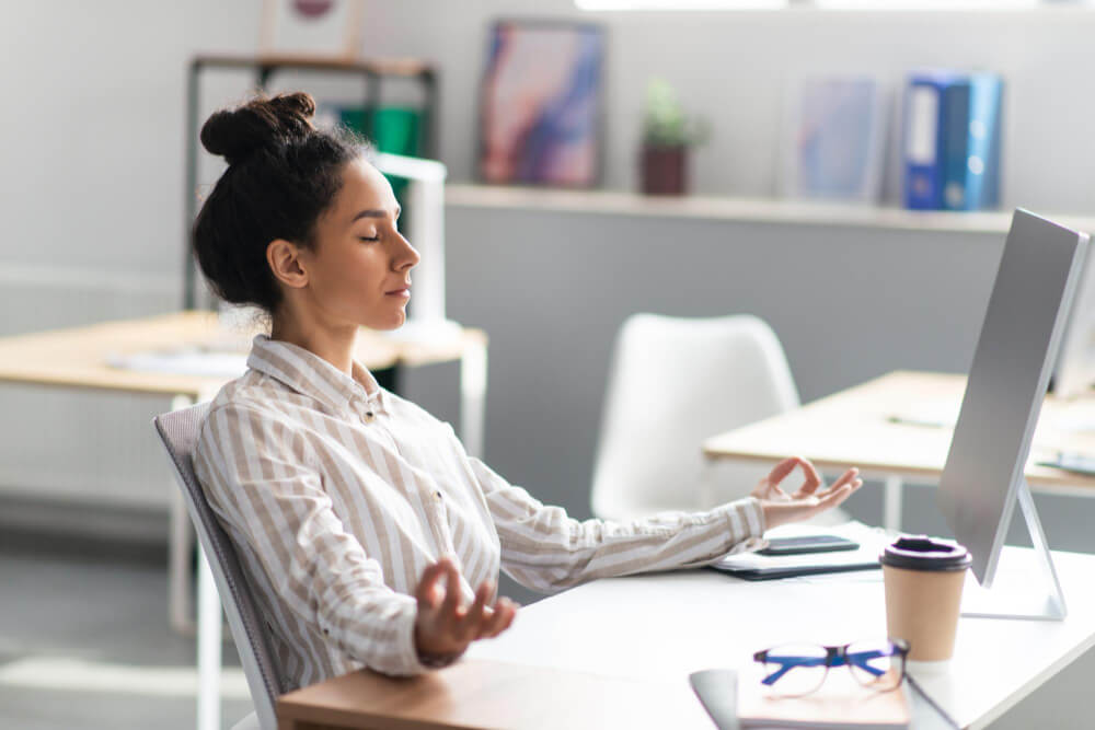Profissional praticando mindfulness no trabalho, sentado em uma mesa de escritório com um ambiente tranquilo ao redor.