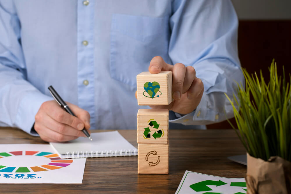 Escritório com ambiente sustentável, com plantas, iluminação natural e colaboradores adotando práticas ecológicas no dia a dia.